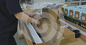 Packing the goods in a box. A woman packer packs a product into a box. Packer work in a factory