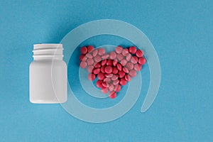 Packing pills. Heart shape made of pills. Pills spilling out of a jar on a blue background