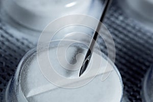 Packing of pills and a needle from a syringe, macro