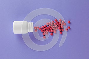 Packing pills. A scattering of pills. Pills spilling out of a jar on a purple background