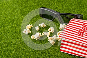 Packing with popcorn on a green lawn with 3D glasses for watching a movie. Grass Watching films about nature. In parks. Recreation