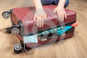 Packing a suitcase with a medical mask. opening of the tourist season after the pandemic