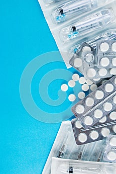 Packs of white pills and syringes on a blue background