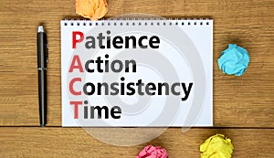 PACT patience action consistency time symbol. Concept words PACT patience action consistency time on white note, wooden background