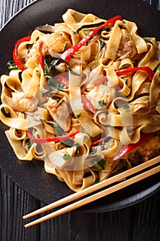 Pad kee mao rice noodles with chicken, basil, chili pepper and sauce close-up on a plate. Vertical top view