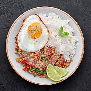 Pad Krapow Gai - Thai Basil Chicken with Rice and fried Egg black slate background. Pad Krapow is Thai cuisine dish