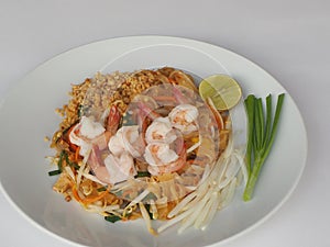 Pad Thai with fresh shrimp and sprinkled with peanuts is placed in a white plate.