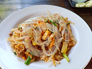 Pad Thai with minced pork and tofu on a white plate on the brown table popular Thai food
