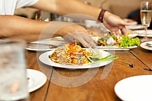 Pad Thai noodles with shrimp on whit plate on wooden table in restaurant.