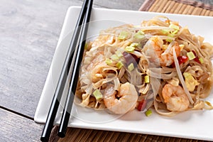 Pad Thai with shrimp and vegetables on wooden table