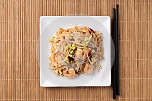 Pad Thai with shrimp and vegetables on wooden table