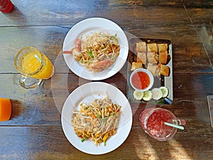 Pad Thai on the table served with orange juice, Roselle juice and fried spring rolls. popular Thai food, Top view