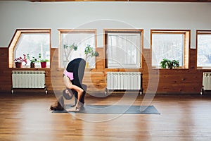 Padahastasana. Beautiful yoga woman practice in a training hall background. Yoga concept.
