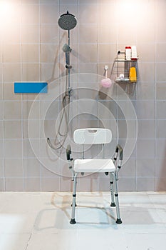 Padded shower chair with arms and back in bathroom with bright t