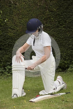 Padding up Lady cricketer putting on leg pads