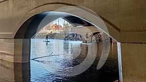 Paddle Boarders pass beneath a city bridge on the Boise River in Idaho
