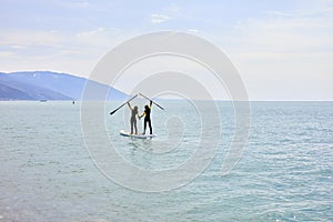 Paddle boarders. young man and woman on stand up paddleboard at sea, rear view