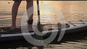 paddle boarding at lake during shining wather surface and propelling on sunset Slow Motion