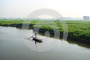 Paddle boat along canal in rapeseed field at morning