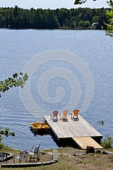 Paddle boat and row of red and yellow Muskoka chairs casting shadows on dock at Spring Lake