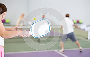 Paddle-shaped racquet for pickleball in hand of female player