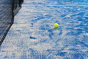 Paddle tennis ball on the court with the net on the background