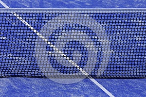 Paddle tennis net and blue court field background. Close up