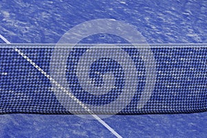 Paddle tennis net and blue court field background. Close up