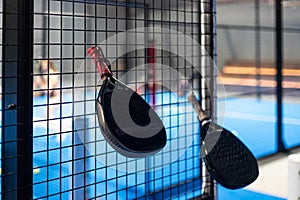 Paddle tennis: Padel racket and ball in front of an outdoor court.