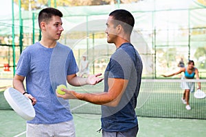 Paddle tennis players friendly talking after match on outdoor court