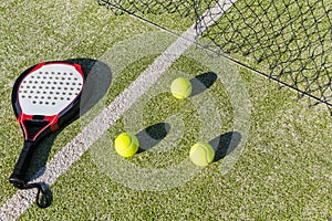 Paddle tennis racket, balls and net on court