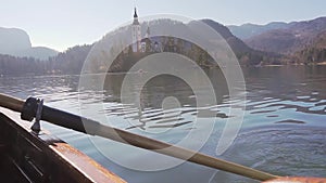 A paddle in the water on a sunny day - Rowing the boat with island Lake Bled in the background- Lake Bled, Slovenia