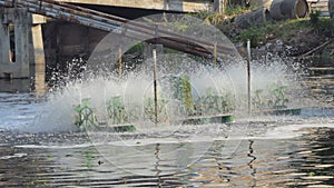 Paddle wheels aerators in black water on canal.