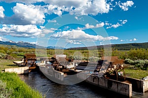 Paddle wheels in a small creek in a meadow near a mountain range