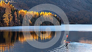 On paddleboard in mountain lake in autumn