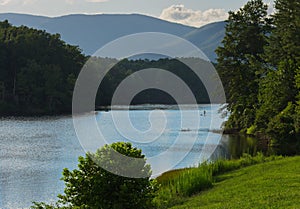 A paddler on a paddleboard enjoys a summer afternoon on a pristine lake