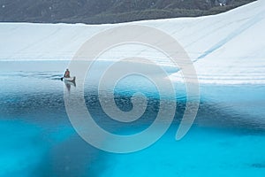 Paddling a canoe across a blue glacier lake in the rain. Matanuska Glacier deep blue pool supraglacial lake