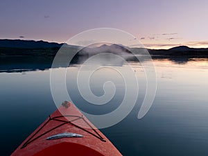 Paddling in a kayak through calm sunset waters