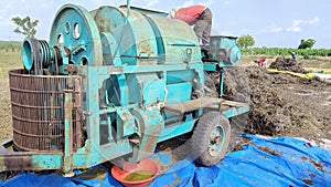 Paddy thresher machine on the agriculture field behind hey stack