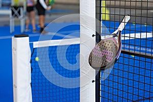 Padel Racket Strung in the Outdoor Structure Surrounding the Playing Field and Players in the Background