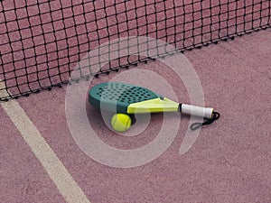 Padle Tennis Racket and Ball on Floor Beside Court Net