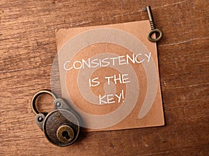 Padlock and brown card with the word CONSISTENCY IS THE KEY