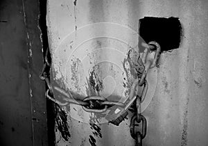 Padlock and chain on a rustic corrugated iron wall - black and white