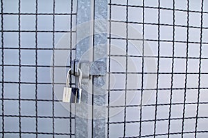 Padlock on a chainlink fence / Master key and old rusty chain with steel cage, close up / Closed lock with chain on metal fence.