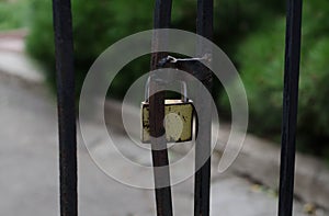 Padlock on the gate. Closed door. Metal fence. Vintage padlock. Closed door. Security system.