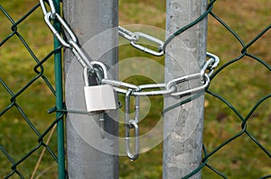 A padlock hanging at a chain-link fence