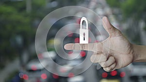 Padlock icon on finger over blur of rush hour with cars and road in city, Technology internet security and safety online conc