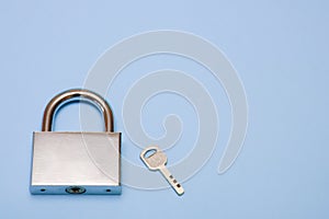 padlock and key on a blue background with copy space, security, reliability