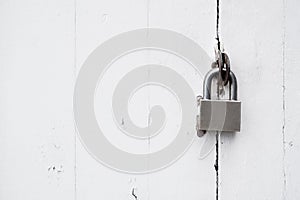 Padlock on rustic white distressed wooden door.