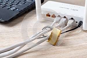Padlock on a Wi-Fi router network cables near laptop on the desk. Concepts of forbidden or limited Internet connection and